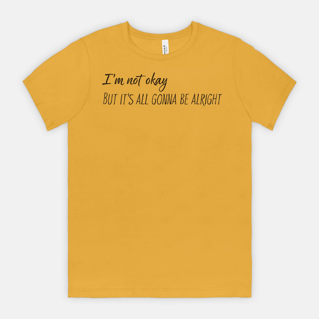 Mustard t-shirt with text 'I'm not okay, but it's all gonna be alright' on a white background