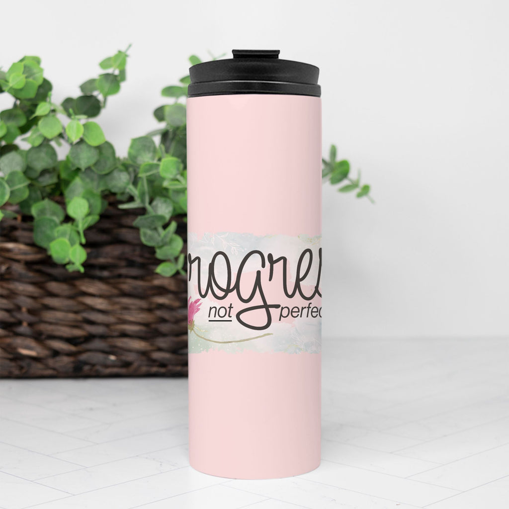 Pink tumbler with black lid and text Progress not Perfection on a Pink background