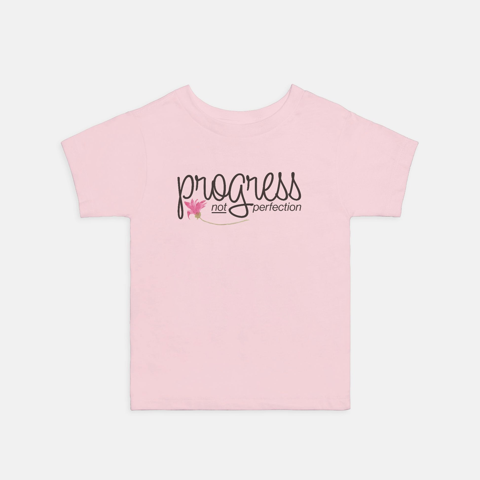 Pink t-shirt with 'progress not perfection' text on a light gray background