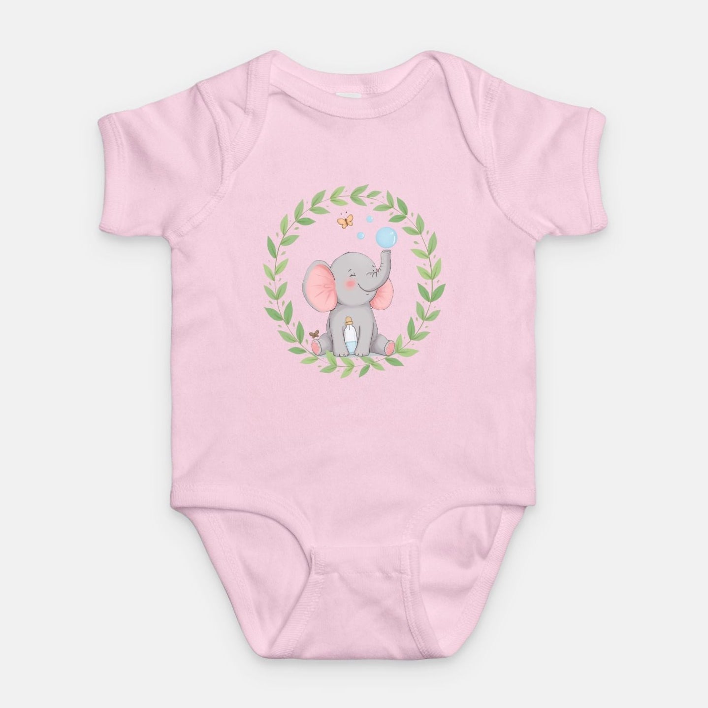 Little Chaos Crew elephant sitting with eyes closed, blowing bubbles beside a tipped bubble bottle inside green leafy wreath, minimalist baby pink onesie design.