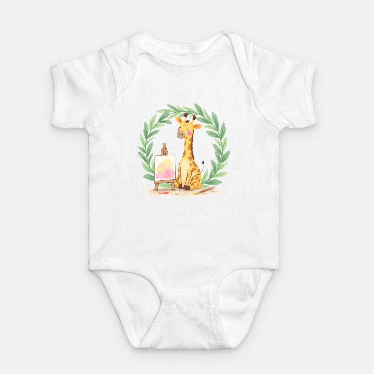 Little Chaos Crew giraffe sitting with eyes closed beside an easel and paintbrush inside green leafy wreath, minimalist baby white onesie design.