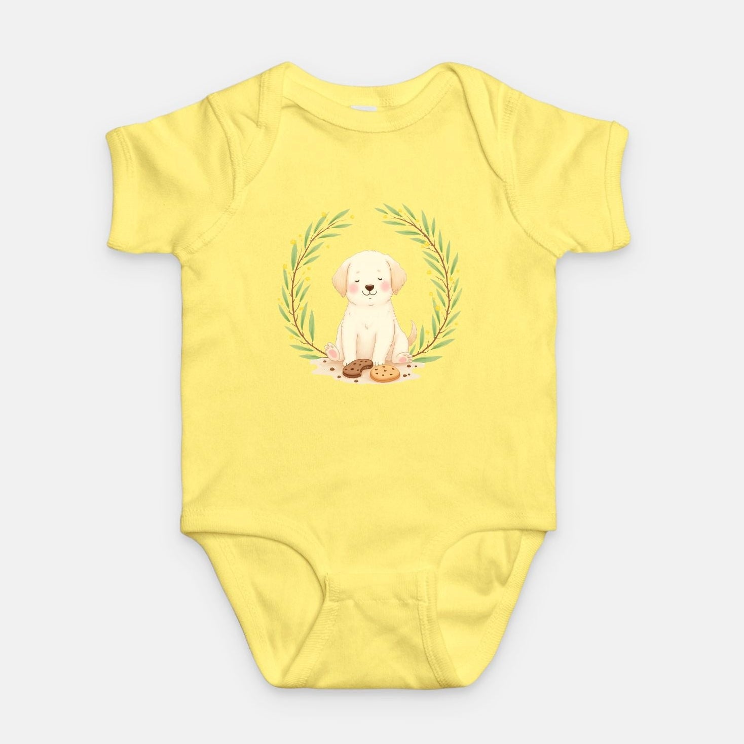 Little Chaos Crew puppy sitting with eyes closed surrounded by cookies and crumbs inside green leafy wreath, minimalist baby butter onesie design.