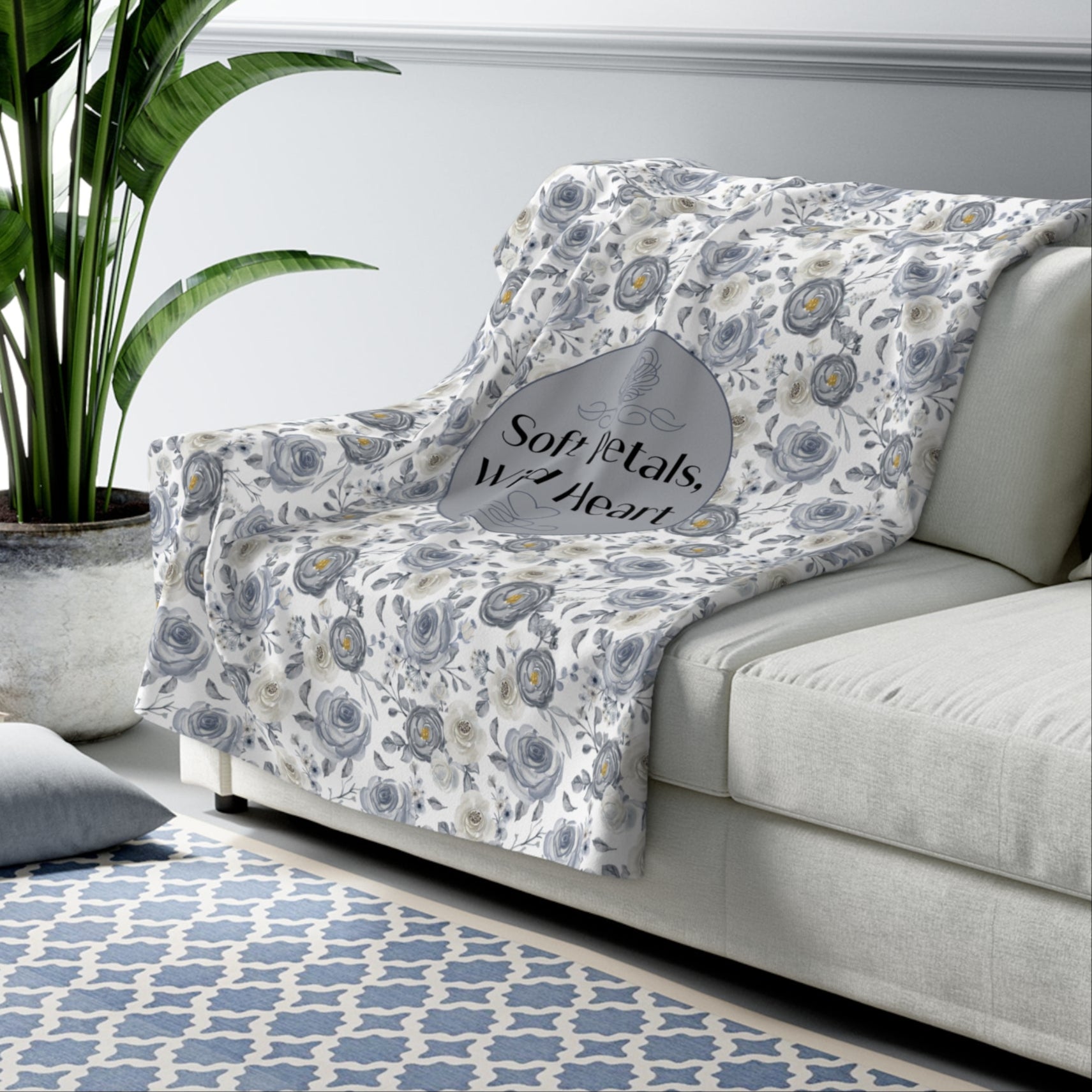 White sofa with floral-patterned with text Soft Petals Wild Heart minky blanket in a living room setting.